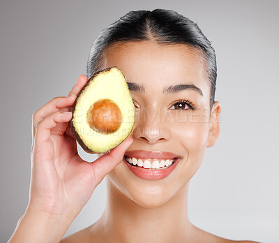 Buy stock photo Studio shot of an attractive young woman holding an avocado to her face against a grey background