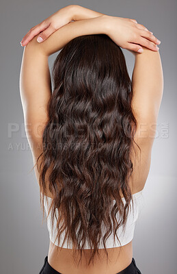 Buy stock photo Rearview shot of a young woman with long curly hair posing against a grey background