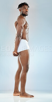 Buy stock photo Studio shot of a handsome young man flexing his muscles