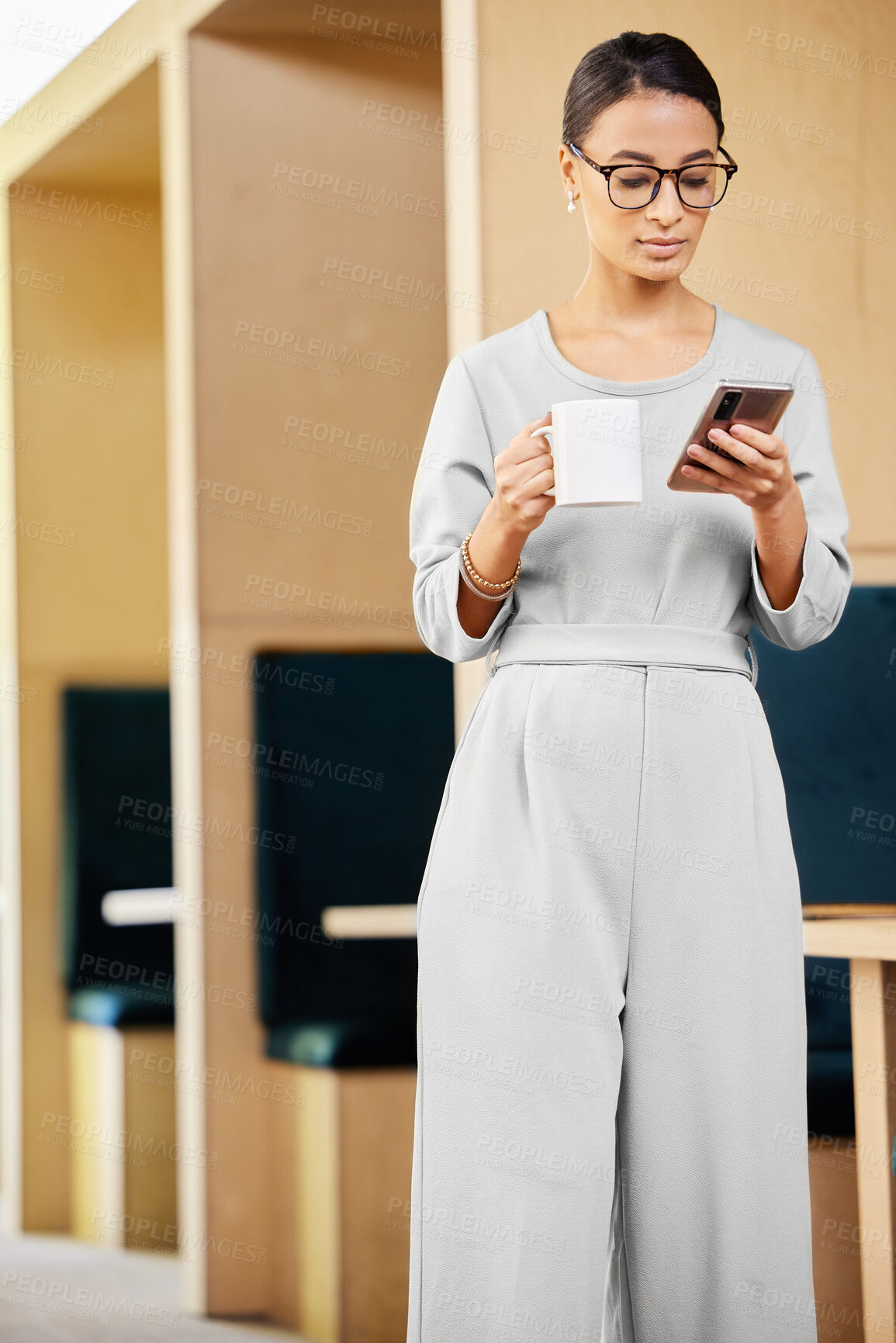 Buy stock photo Cropped shot of an attractive mature businesswoman checking her messages while standing in the office