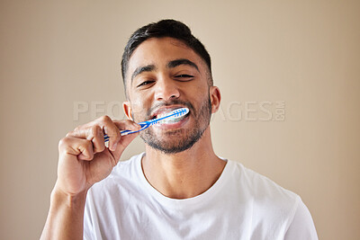 Buy stock photo Studio shot of a handsome young man brushing his teeth against a studio background