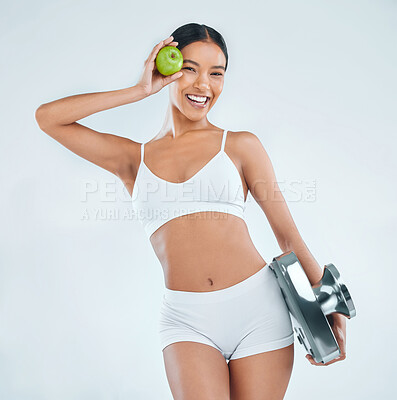 Buy stock photo Happy woman, portrait and apple with scale for nutrition, diet or weight loss on a studio background. Female person or young model with smile for natural organic fruit, vitamin or health and wellness