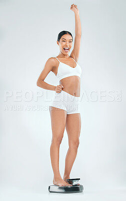 Buy stock photo Excited woman, scale and celebration with weight loss, milestone or achievement in fitness on a studio background. Happy female person or model with smile on weighing machine for good news or results