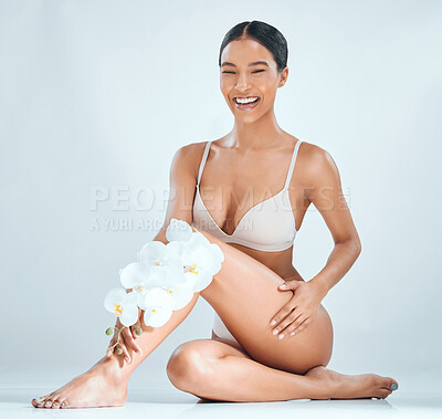 Buy stock photo Woman, flowers and legs in studio for skincare, sustainable cosmetics and vegan beauty. Female person, orchids and organic hair removal or waxing, natural grooming and body treatment for dermatology