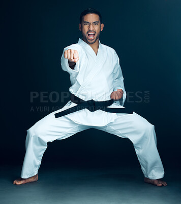 Buy stock photo Full length portrait of a handsome young male martial artist practicing karate in studio against a dark background