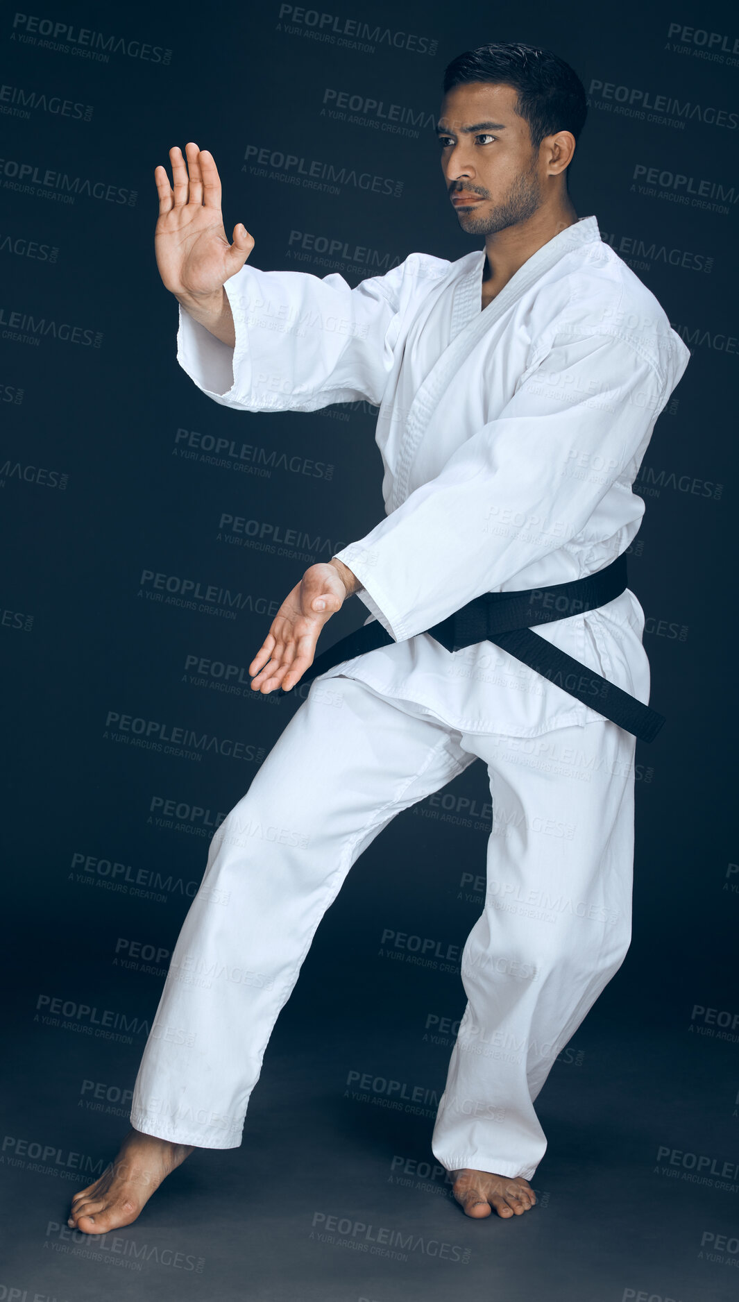 Buy stock photo Full length shot of a handsome young male martial artist practicing karate in studio against a dark background