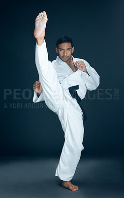 Buy stock photo Full length portrait of a handsome young male martial artist practicing karate in studio against a dark background