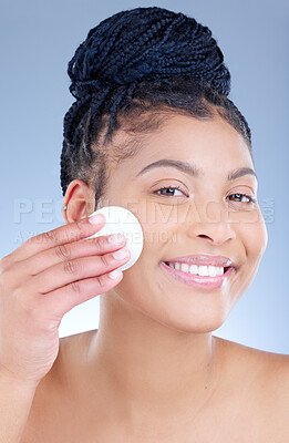 Buy stock photo Studio portrait of an attractive young woman wiping her face with cotton against a blue background