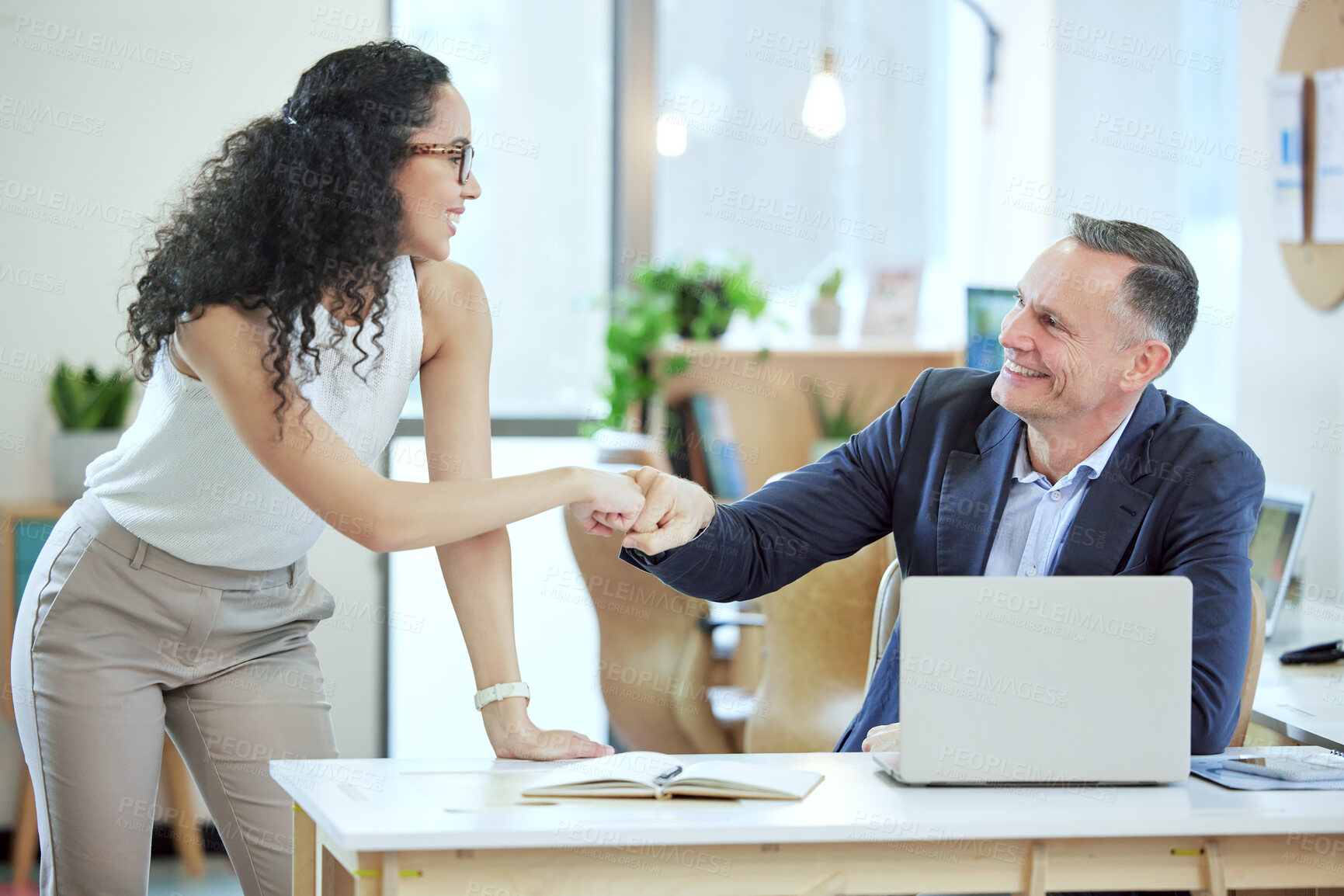 Buy stock photo Shot of two young businesspeople giving each other a fist bump in an office at work