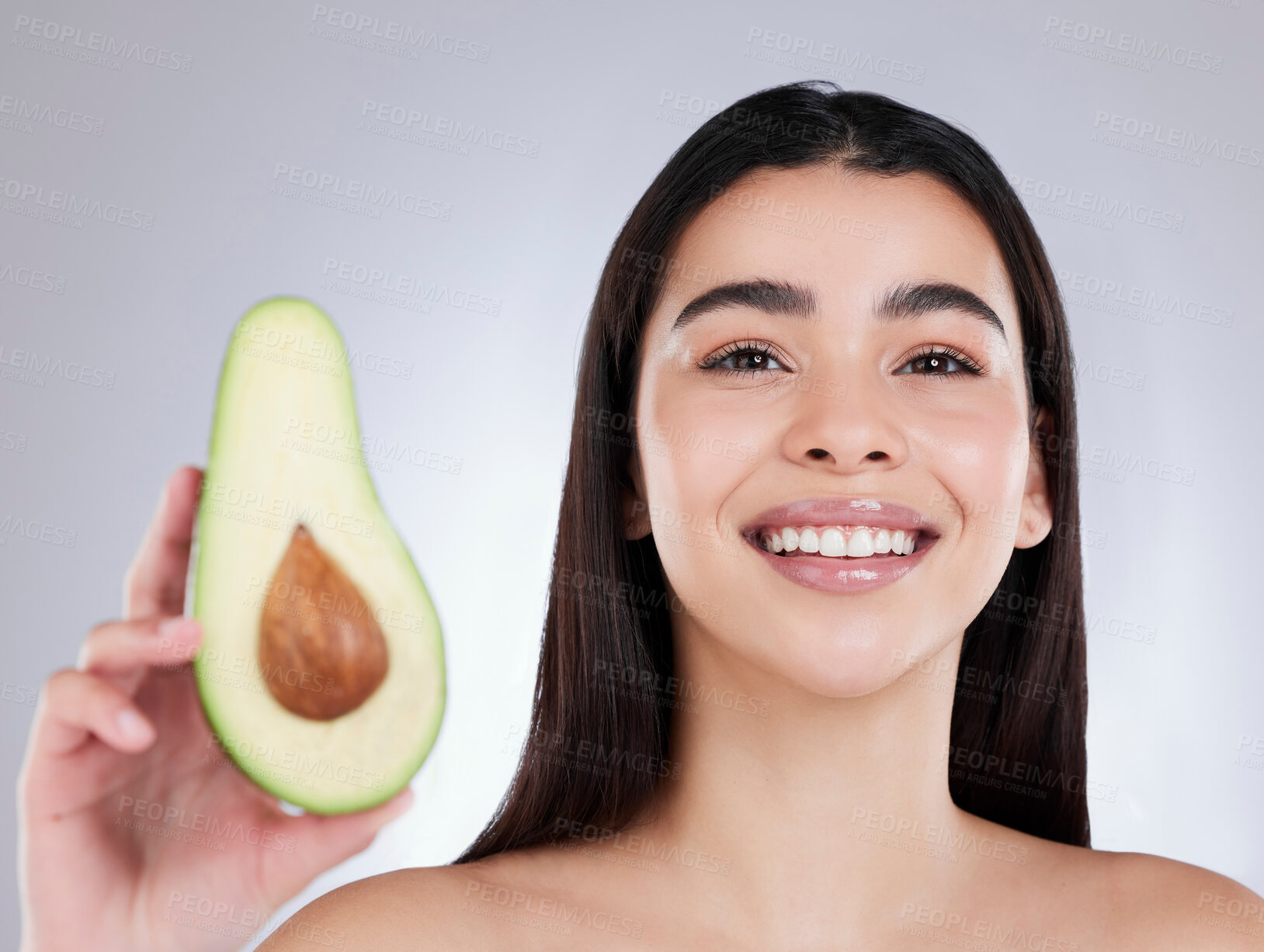 Buy stock photo Studio portrait of an attractive young woman posing with an avocado against a grey background