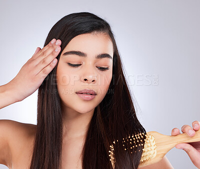 Buy stock photo Studio shot of an attractive young woman brushing her hair against a grey background