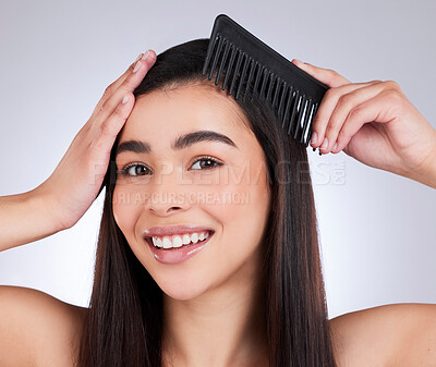 Buy stock photo Studio portrait of an attractive young woman combing her hair against a grey background