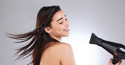 Buy stock photo Studio shot of an attractive young woman using a hairdryer against a grey background