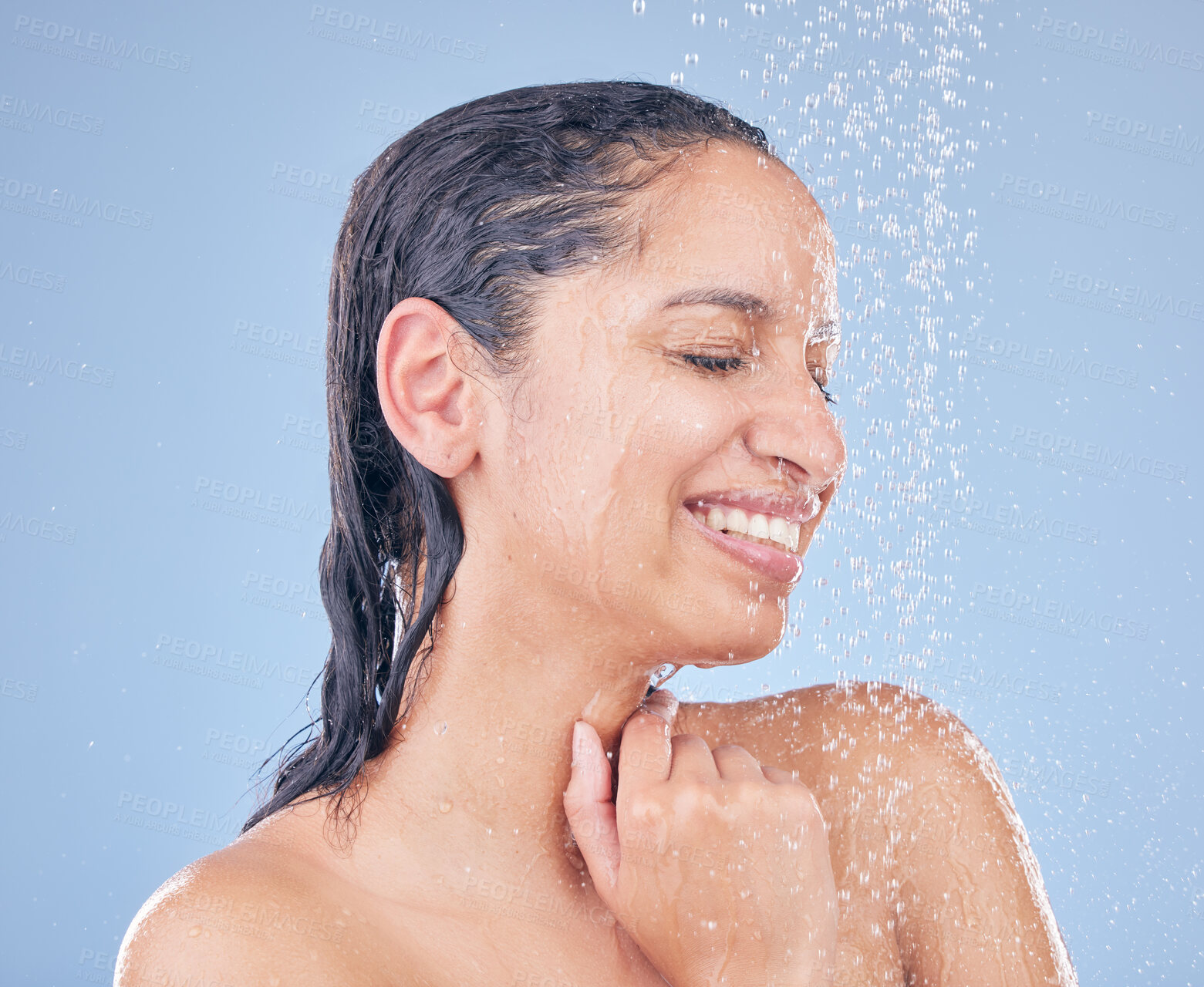 Buy stock photo Shot of a beautiful young woman taking a shower against a blue background