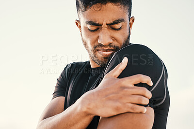 Buy stock photo Cropped shot of a handsome young male athlete holding his shoulder in pain while exercising on the beach