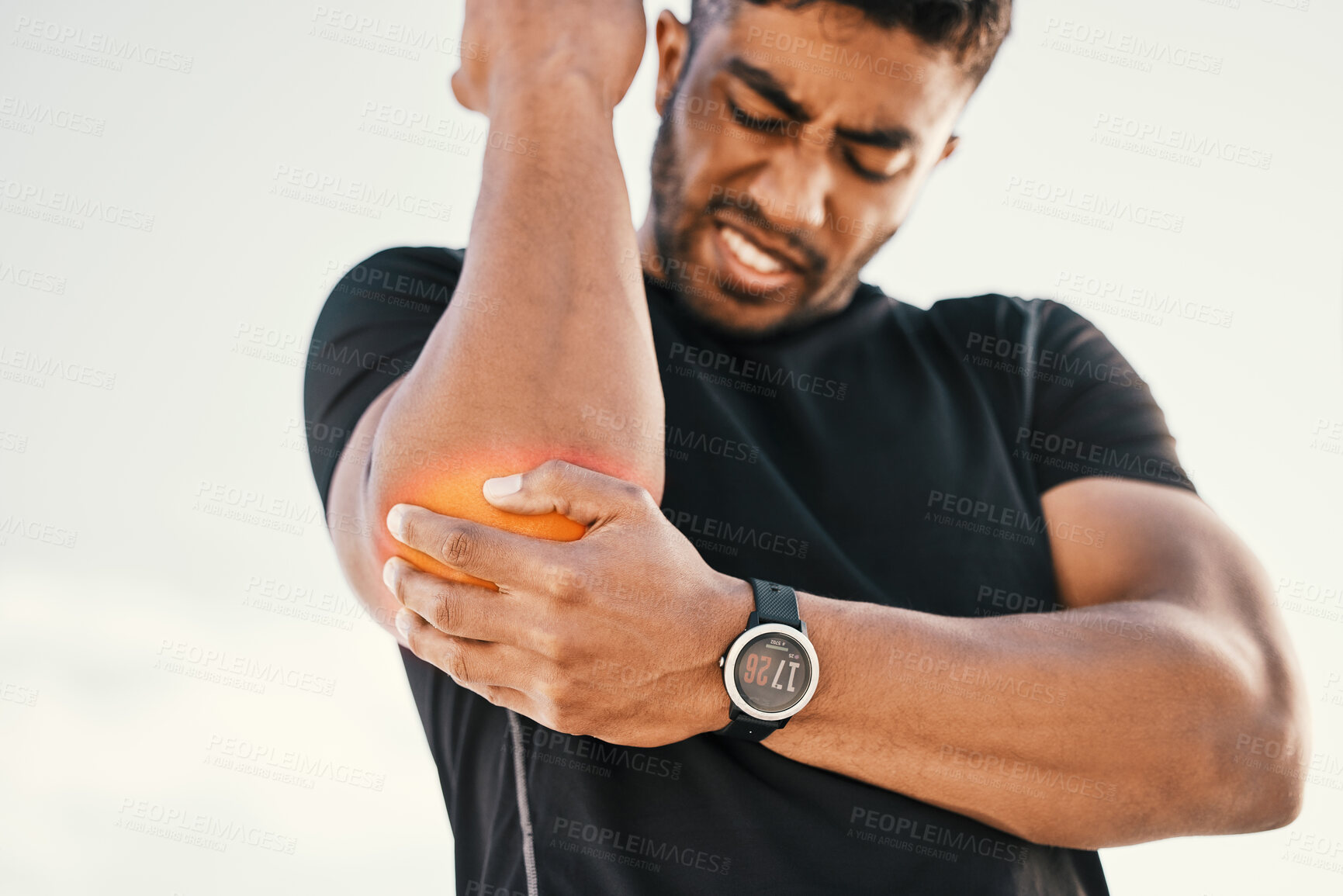 Buy stock photo Cropped shot of a handsome young male athlete holding his elbow in pain while exercising on the beach