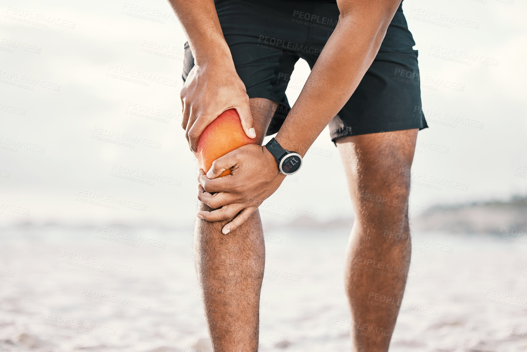 Buy stock photo Cropped shot of an unrecognizable male athlete holding his knee in pain while exercising on the beach