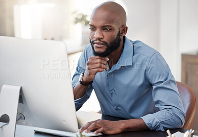 Buy stock photo Cropped shot of a handsome young businessman looking thoughtful while working on his computer in the office