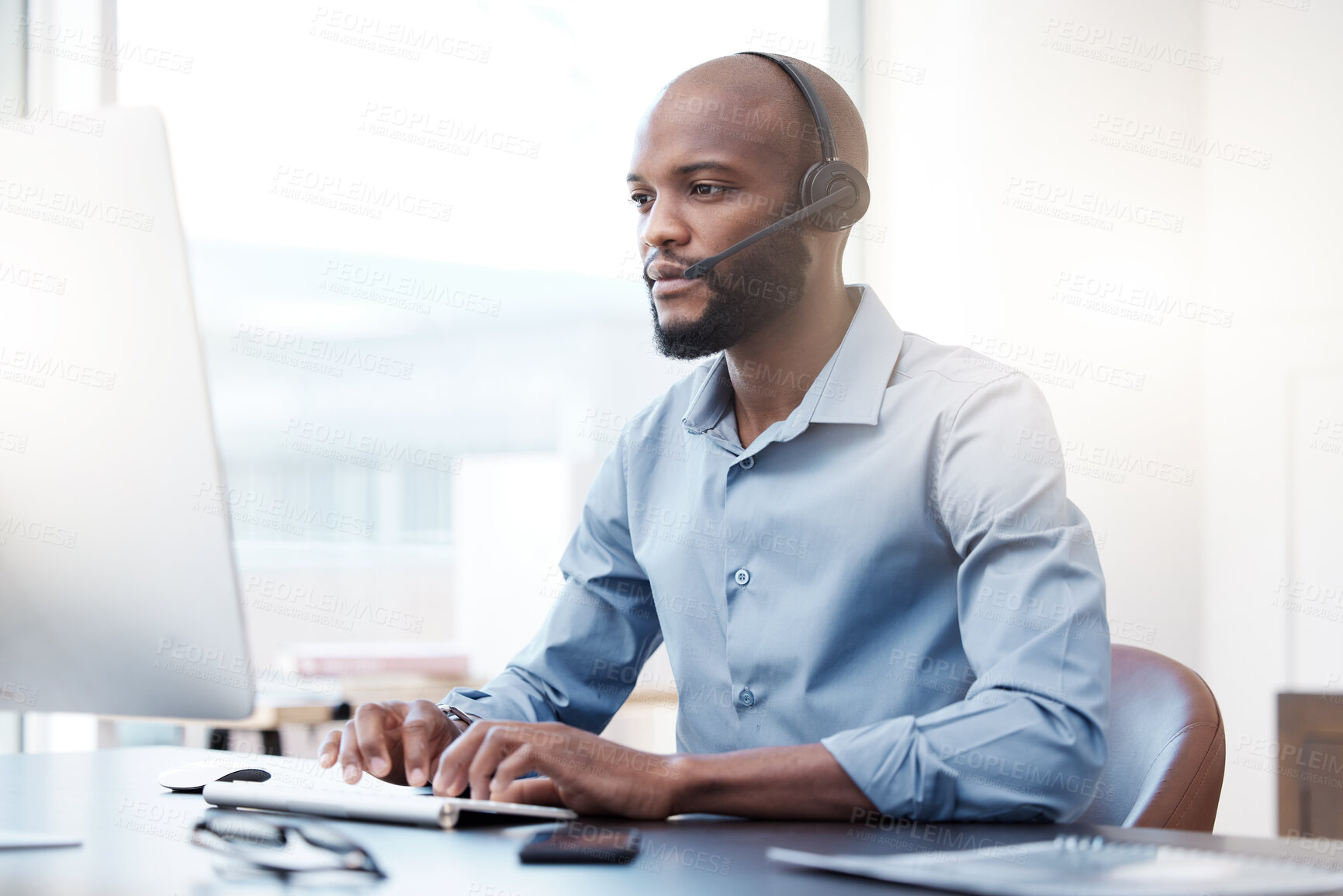 Buy stock photo Cropped shot of a handsome young male call center agent working on his computer in the office