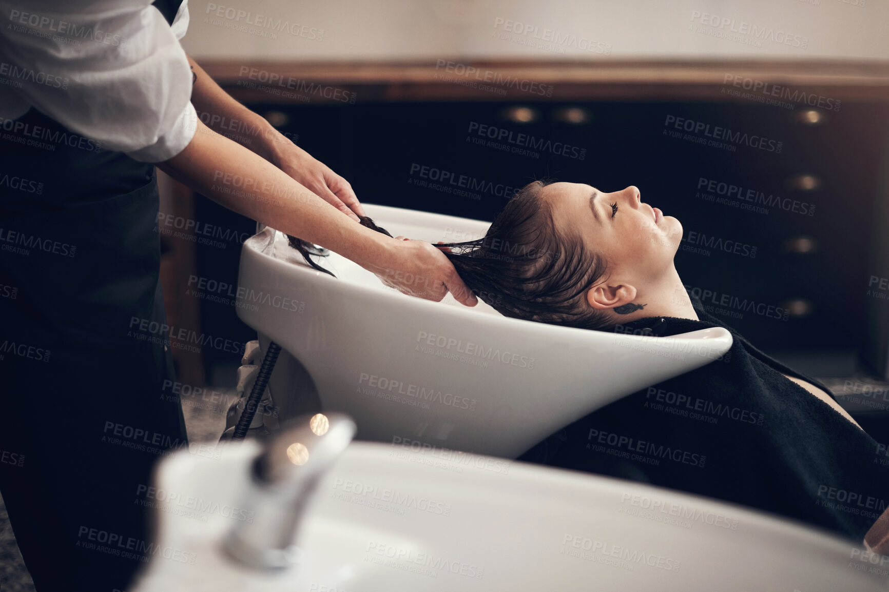 Buy stock photo Woman, salon and hair in basin washing, client and eyes closed or applying treatment with person hands. Professional, hairdresser and haircare with customer, pamper and relaxing service with stylist
