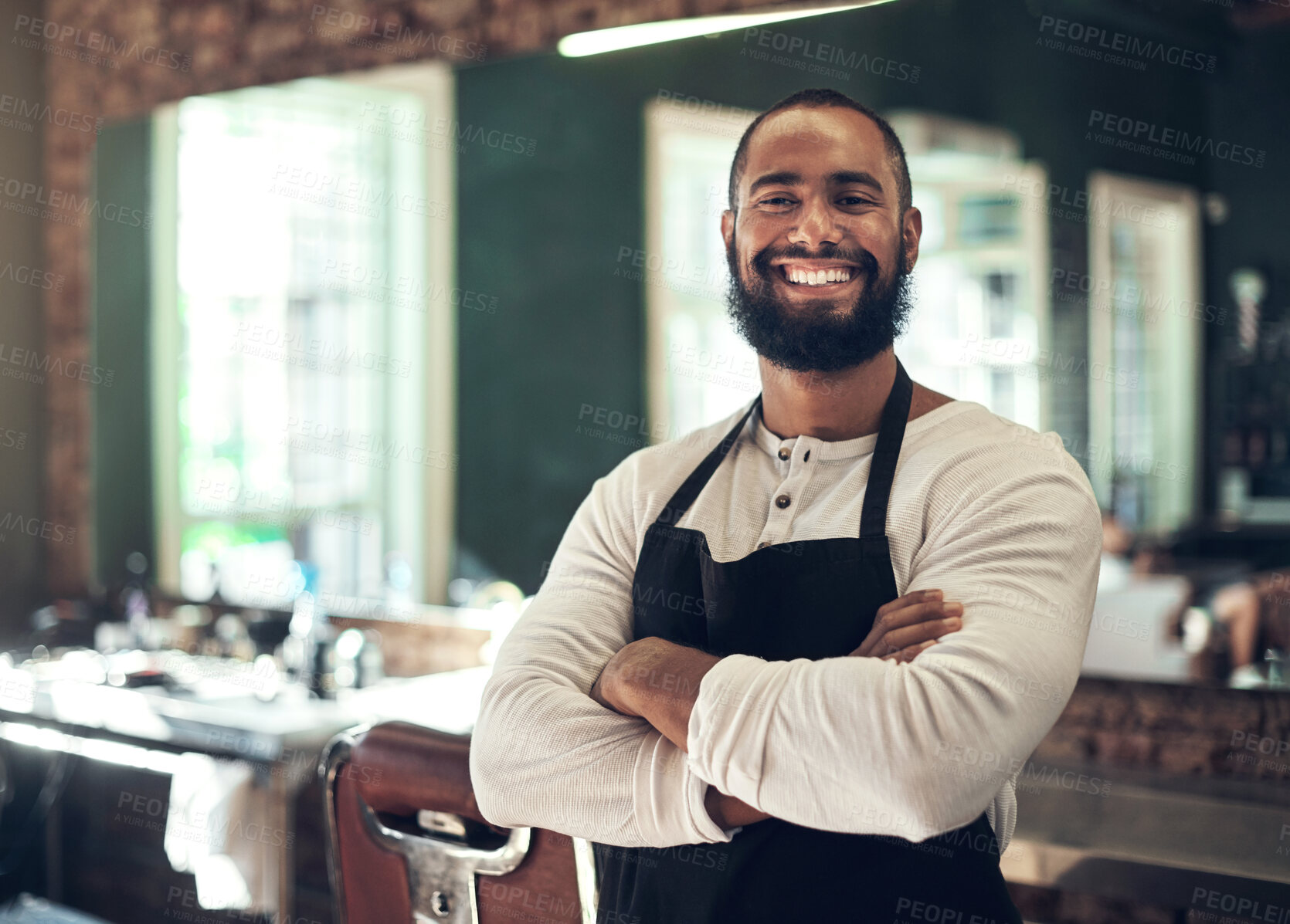 Buy stock photo Shot of a handsome young barber standing alone in his salon with his arms folded