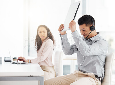 Buy stock photo Shot of a young call centre agent angrily smashing a laptop while working in an office