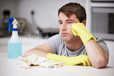 Buy stock photo Male person, bored and sad in kitchen for cleaning in house with spray bottle, soap and disinfectant. Annoyed, frustrated and moody from disinfecting home with risk reduction of flu for hygiene.