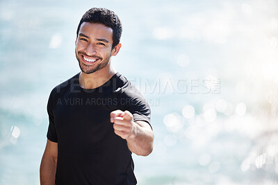 Buy stock photo Cropped portrait of a handsome young male athlete pointing towards the camera while working out on the beach
