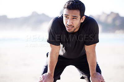 Buy stock photo Cropped shot of a handsome young male athlete looking exhausted during his workout on the beach