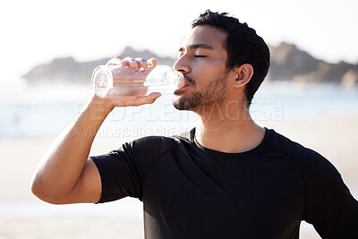 Buy stock photo Cropped shot of a handsome young male athlete hydrating during his workout on the beach