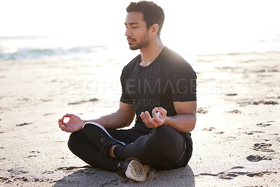 Buy stock photo Full length shot of a handsome young male athlete meditating on the beach