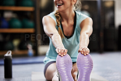 Buy stock photo Shot of a young woman sitting on the floor and stretching at the gym