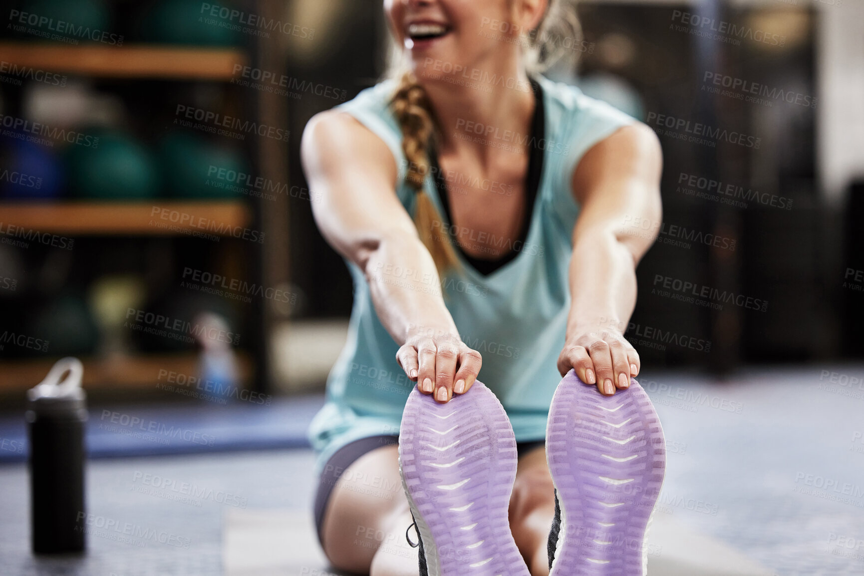 Buy stock photo Shot of a young woman sitting on the floor and stretching at the gym