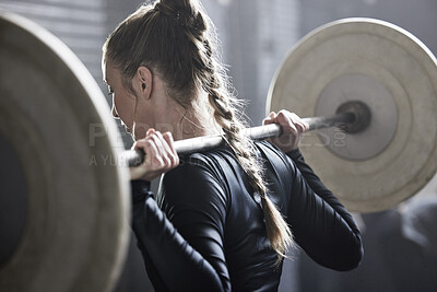 Buy stock photo Shot of an athletic young woman working out with a barbell at the gym