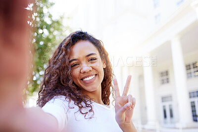 Buy stock photo Shot of a female showing a peace gesture while taking a selfie outside