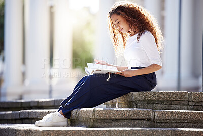 Buy stock photo Shot of a young woman reading a book outside at campus
