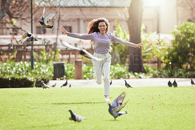 Buy stock photo Shot of a young woman chasing birds at a park