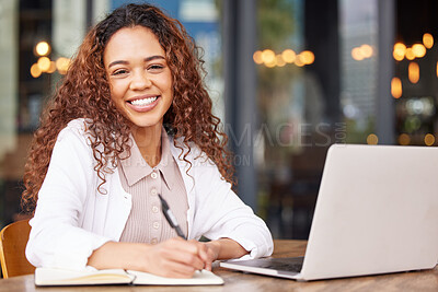 Buy stock photo Shot of a young businesswoman writing in a notebook while using a laptop at a cafe