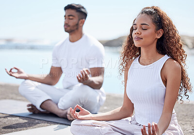 Buy stock photo Cropped shot of a young couple practicing yoga at the beach