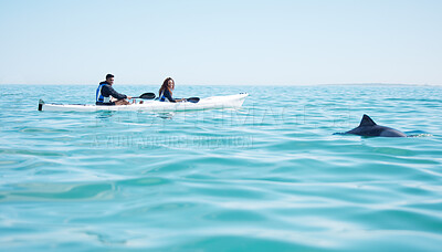 Buy stock photo Shot of a young couple spotting a dolphin while kayaking at a lake