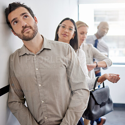 Buy stock photo Shot of a young businessman thinking while waiting in line at an office