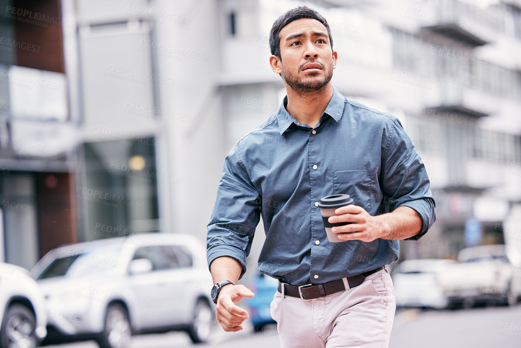 Buy stock photo Shot of a handsome young businessman feeling stressed while walking through the city