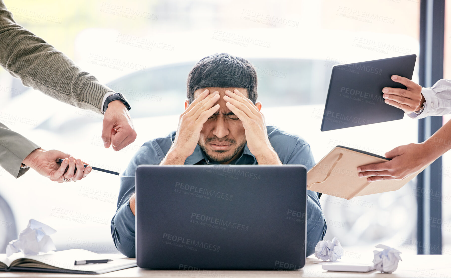 Buy stock photo Shot of a handsome young businessman sitting in the office and feeling stressed while his colleagues put pressure on him