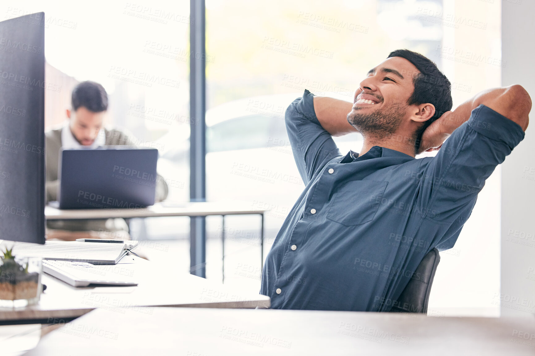 Buy stock photo Shot of a handsome young businessman sitting in the office with his arms behind his head in relief