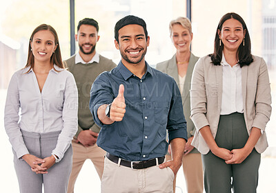 Buy stock photo Shot of a handsome young businessman standing in the office with his colleagues and showing a thumbs up