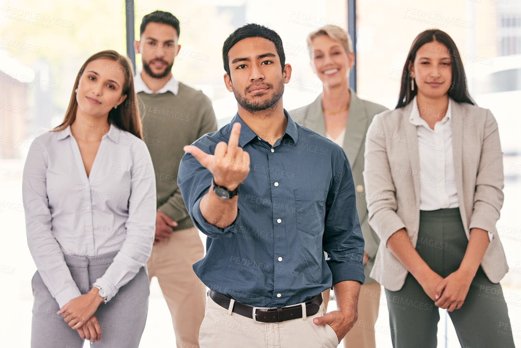 Buy stock photo Shot of a handsome young businessman standing in the office with his colleagues and showing the middle figure