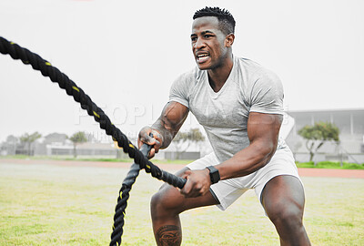 Buy stock photo Cropped shot of a handsome young male athlete exercising with battle ropes outside