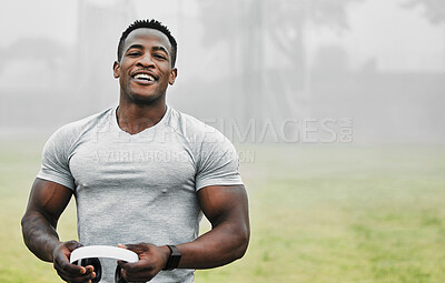 Buy stock photo Cropped portrait of a handsome young male athlete holding a pair of headphones while exercising outside
