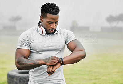 Buy stock photo Cropped shot of a handsome young male athlete checking his smartwatch while exercising outside