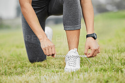 Buy stock photo Cropped shot of an unrecognizable young female athlete tying her laces while exercising outside